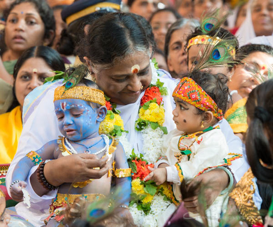 Amma with little children dressed as Krishna sitting on her lap