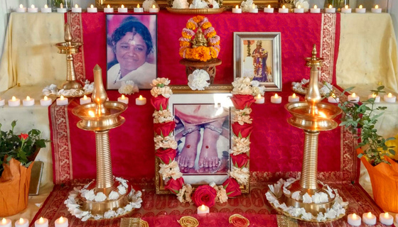 Altar with photos of Amma, fresh flowers and votive lights