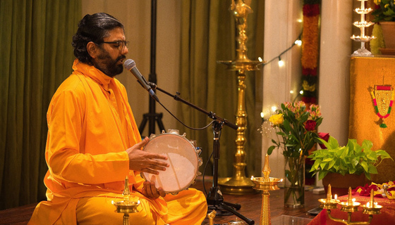 Br. Ramanandamrita Chaitanya singing at a microphone