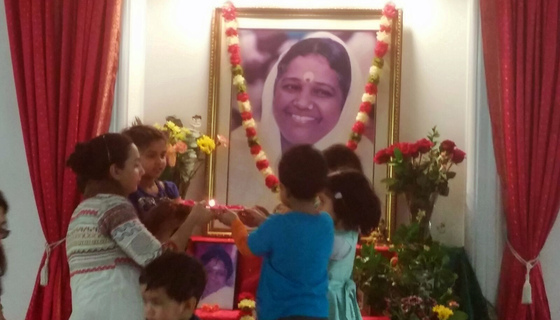 Group of kids doing arati to Amma's picture