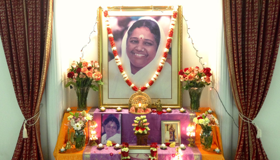 Amma's photo and Ganesha murti, with flowers and lights