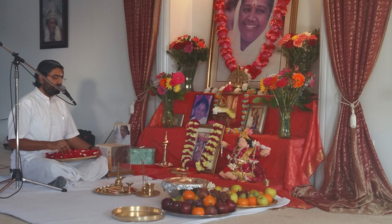 Brahmachari Ramanand seated before altar with flower petals in hand