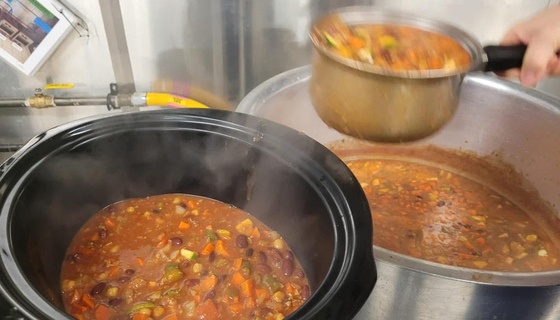Chili being transferred into a crock pot
