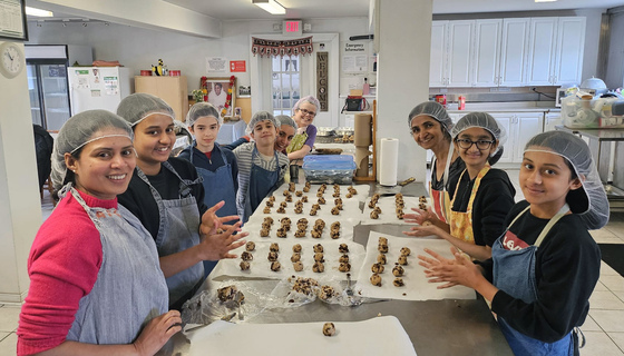 Volunteers shaping oatmeal raisin chocolate chip cookies in Amma Canada kitchen