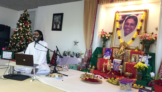 Br. Ramanand speaking at a mic in front of the altar and a Christmas tree