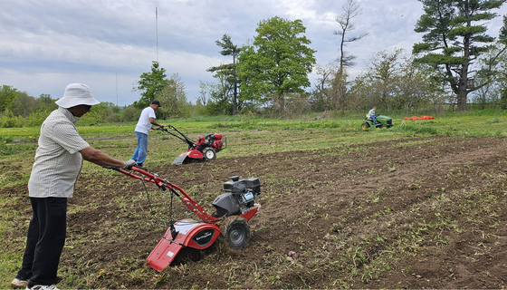 Amma Canada volunteers tilling the vegetable garden beds