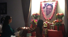 Mother and daughter doing arati together in front of Amma's photo