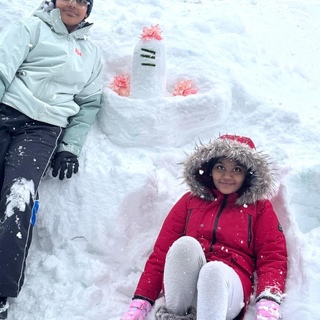 Two children next to a large Siva Lingam they made out of snow