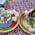 Two baby Krishna murtis with fresh flowers