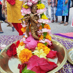 A brass Krishna murti with fresh flower garland