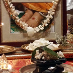 Black stone Shiva lingam and Nandi in front of garlanded photo of Amma's feet