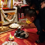 Mother and baby pouring milk on black stone Shiva lingam and Nandi