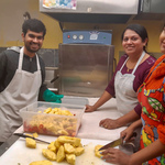 Youth and mentor smiling while chopping fruits