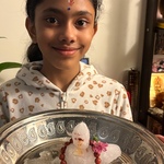 Child holding a silver plate containing a small Siva Lingam made from snow