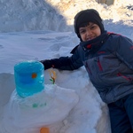 Child next to Siva Lingam they made out of blue ice and snow