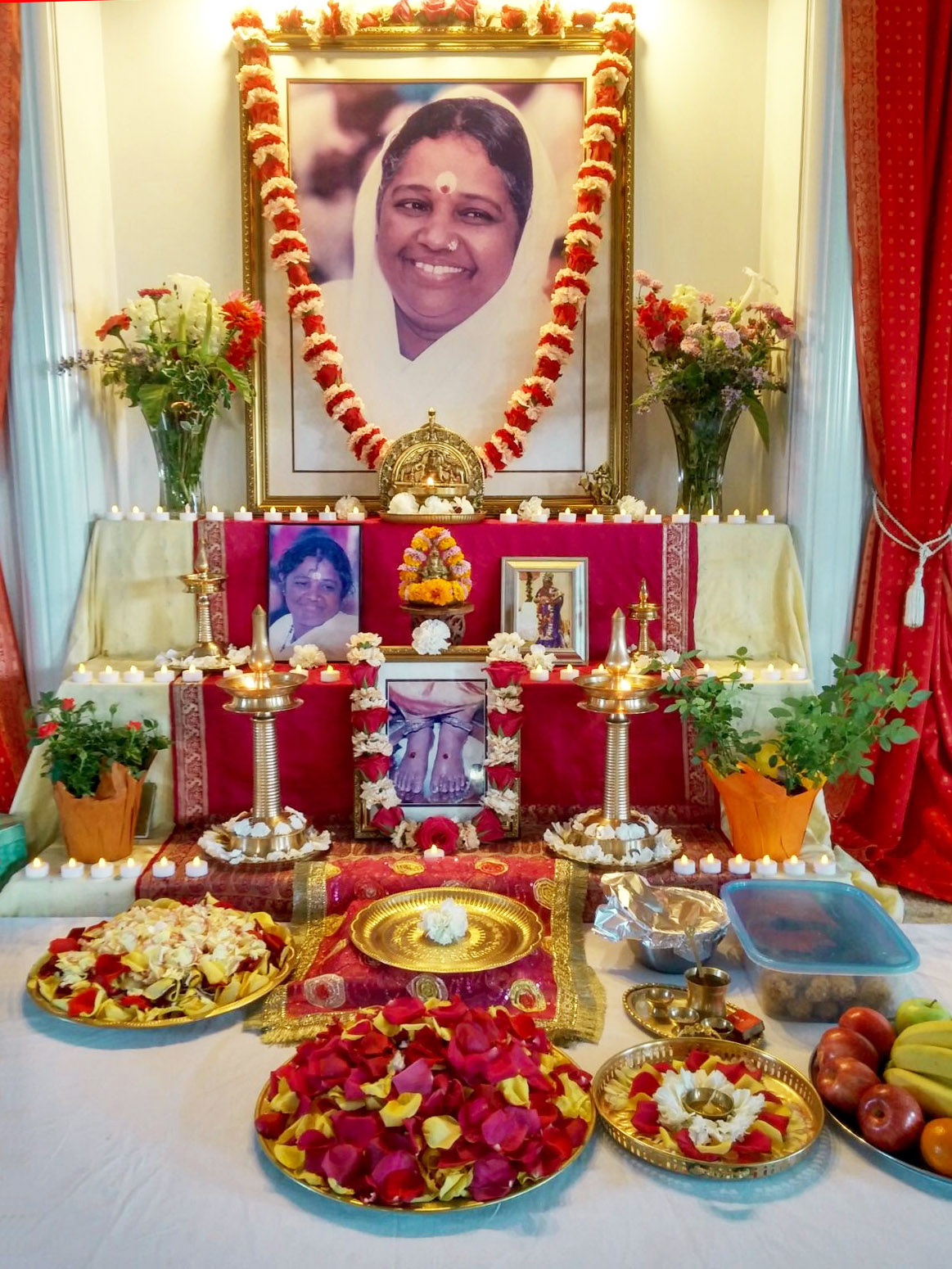 Altar with Amma's portrait, fresh flowers, and many votive candles