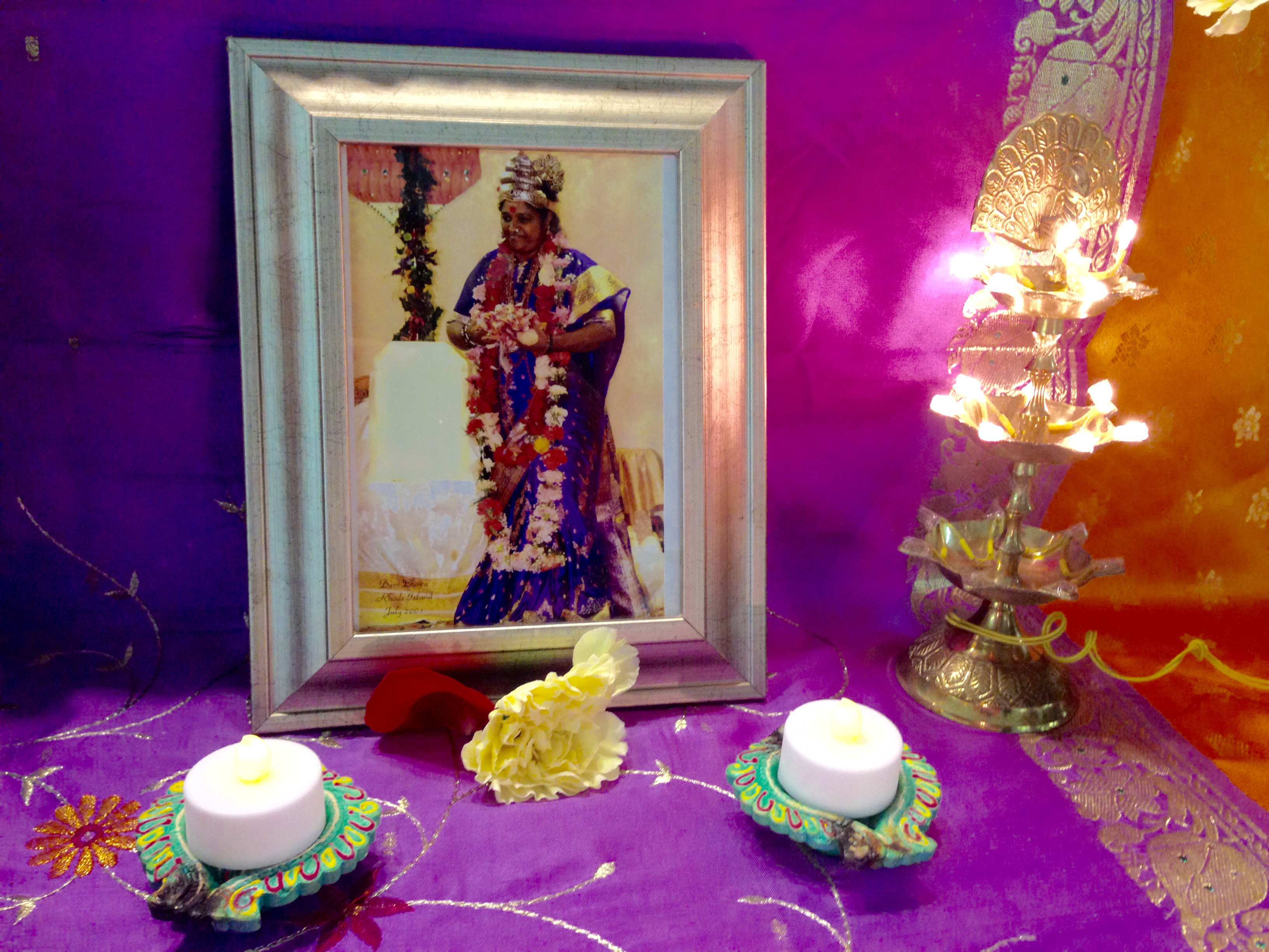 Flowers before photo of Amma in Devi Bhava next to a lit Lamp