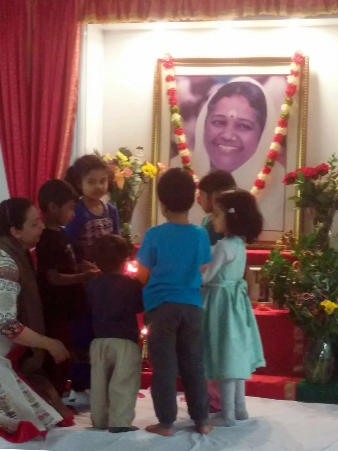 Children doing arati to Amma's photo