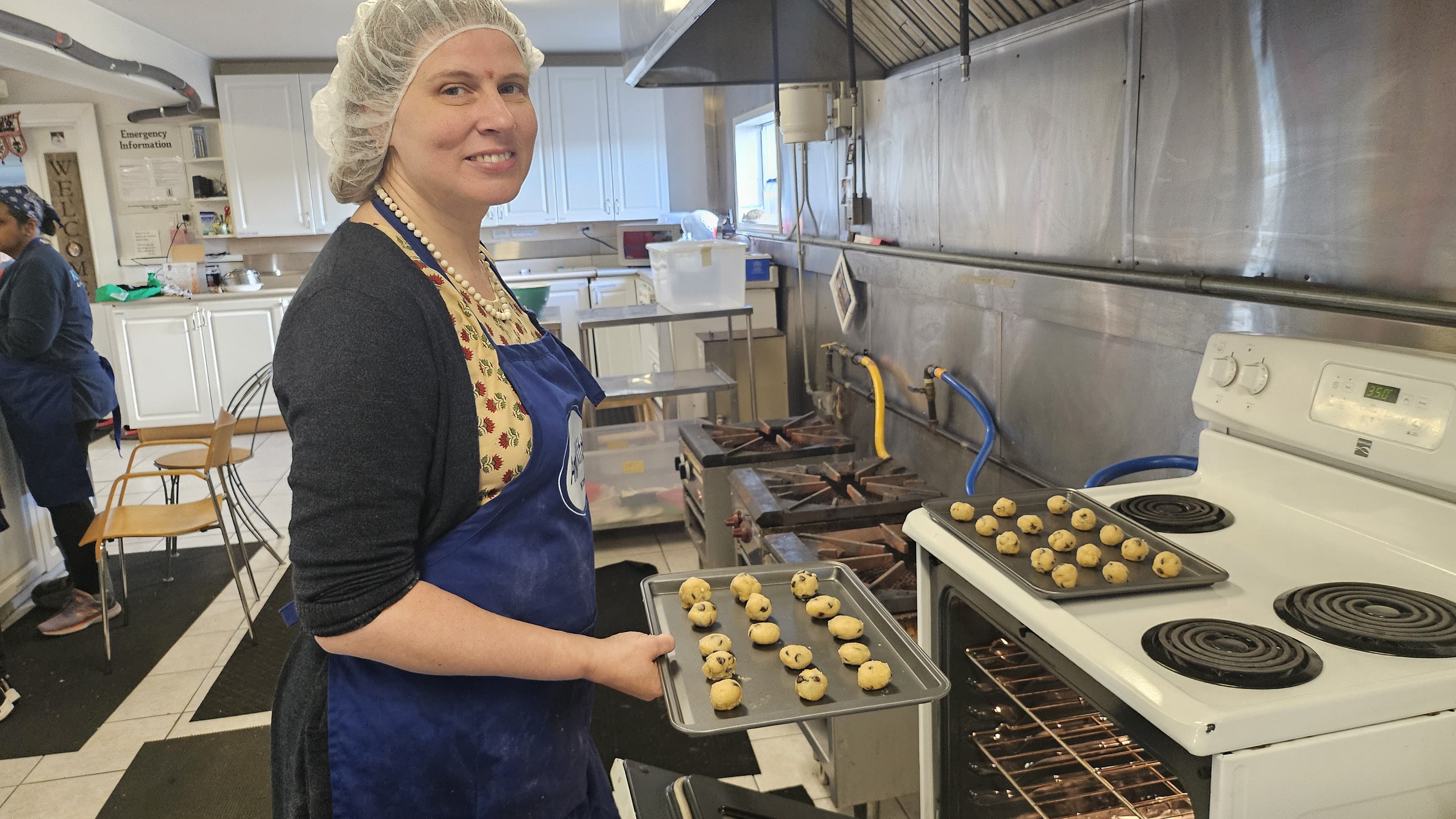 Amma Canada volunteer putting chocolate chip cookies in the oven