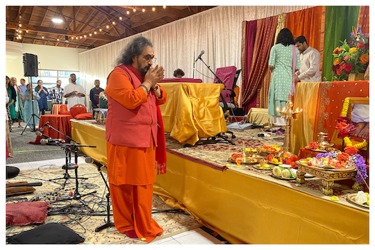 Swamiji praying at the altar on stage to start the program