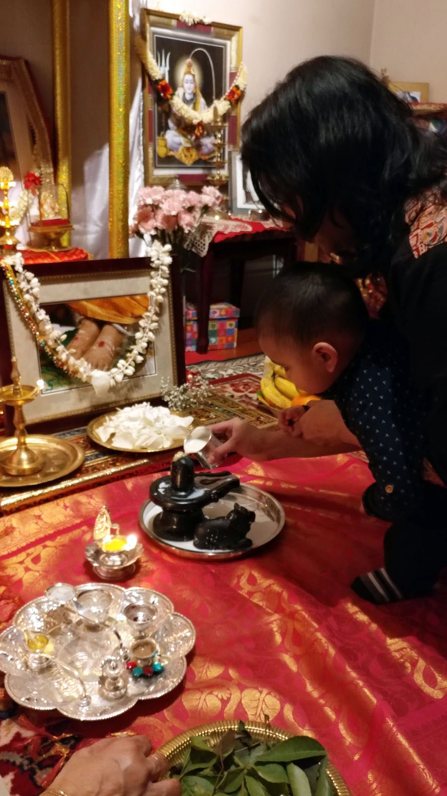 Mother and Baby pouring milk on Shiva Lingam and Nandi on silver plate
