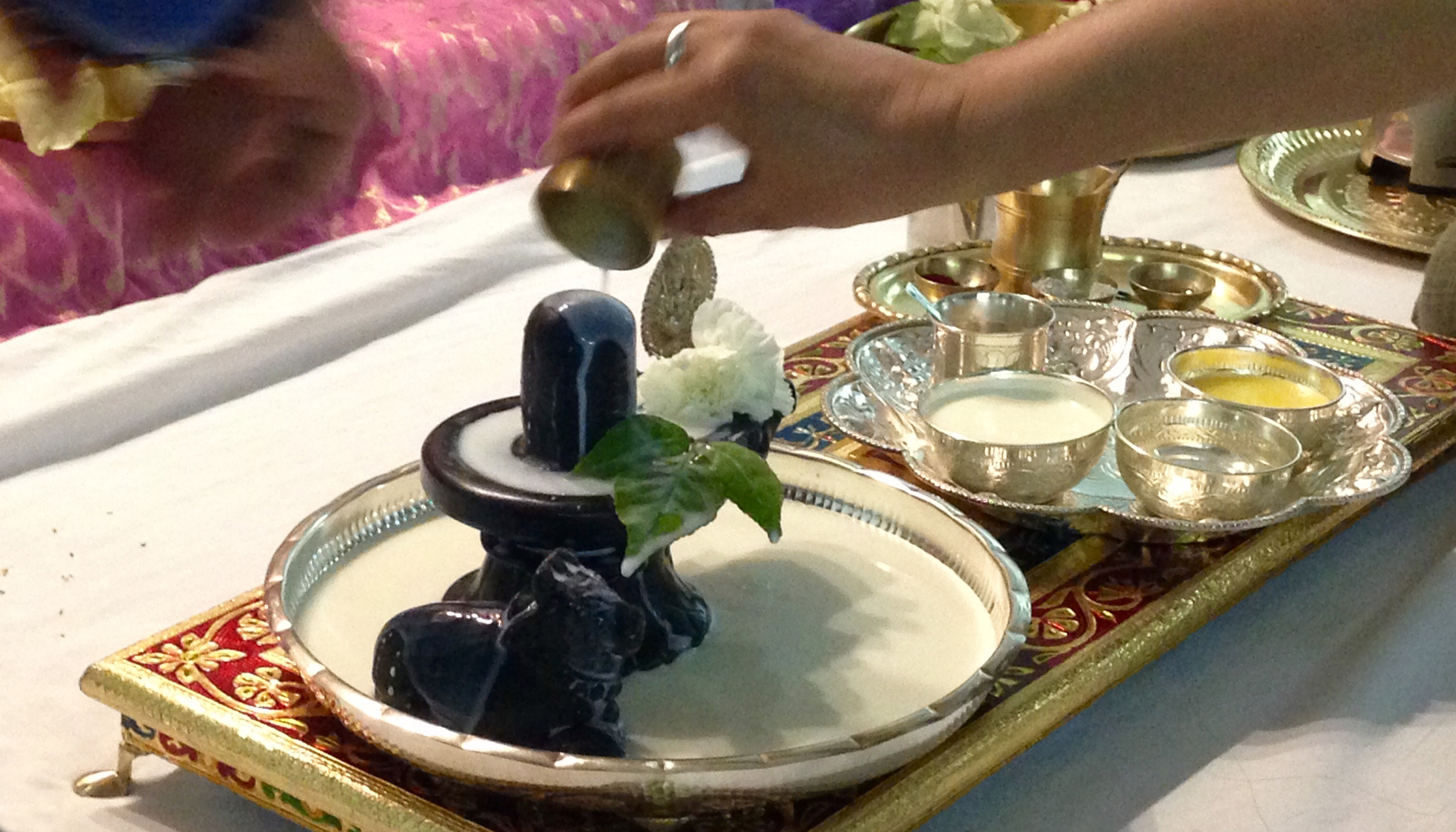 Pouring milk on dark stone Shiva Lingam