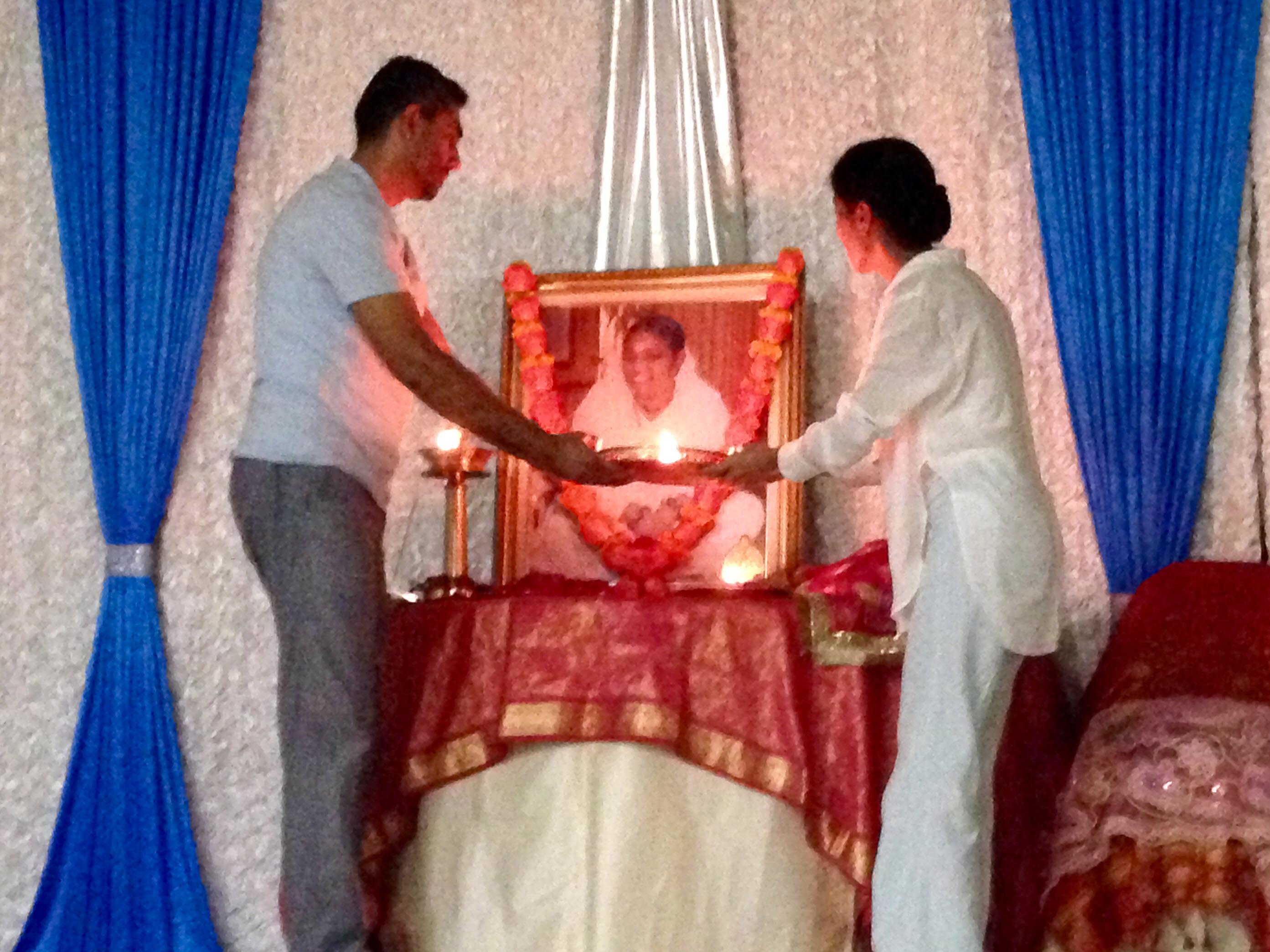 A couple doing arati to Amma's picture