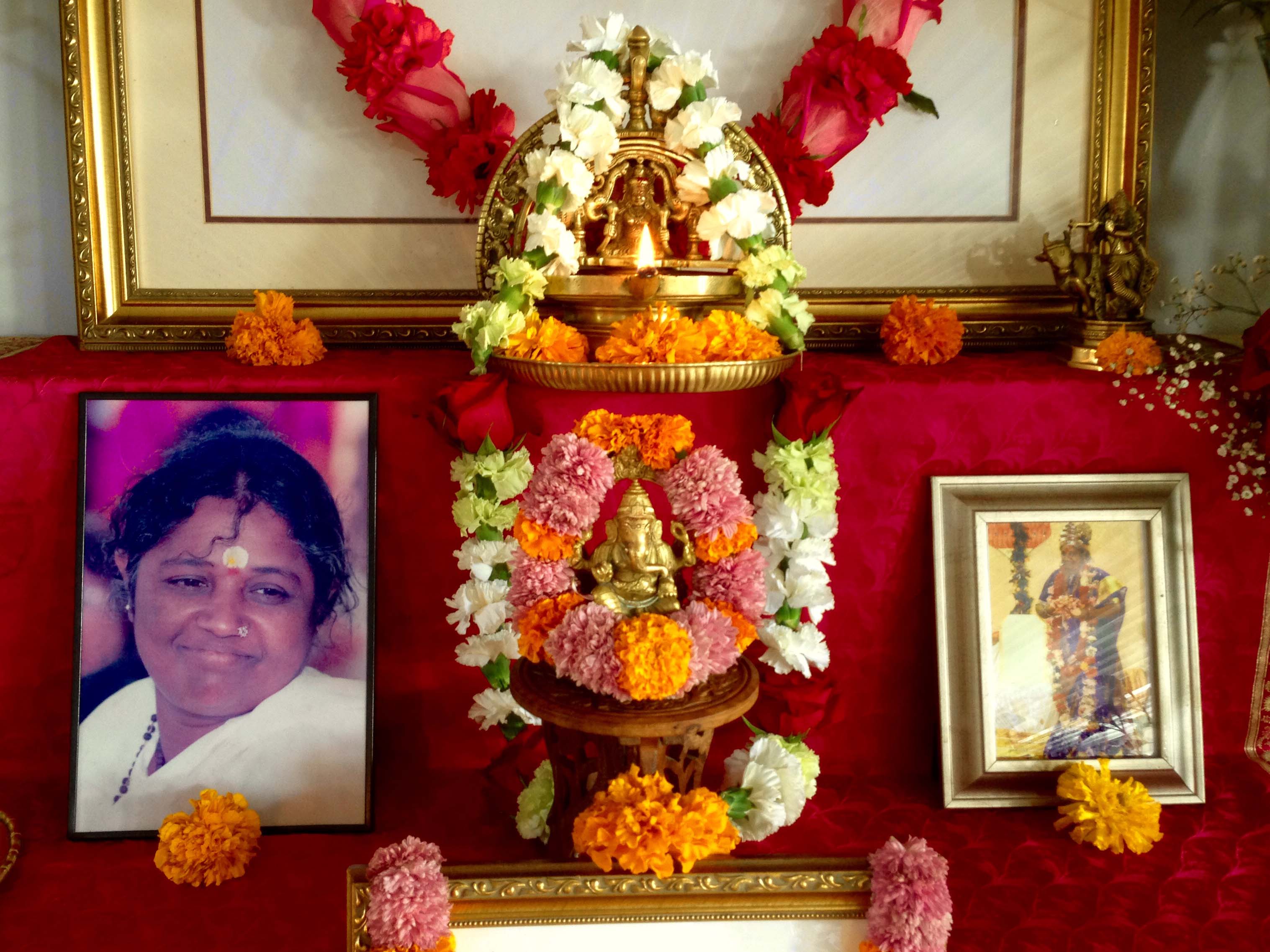 Ganesh murti and Amma's pictures on altar with fresh flowers