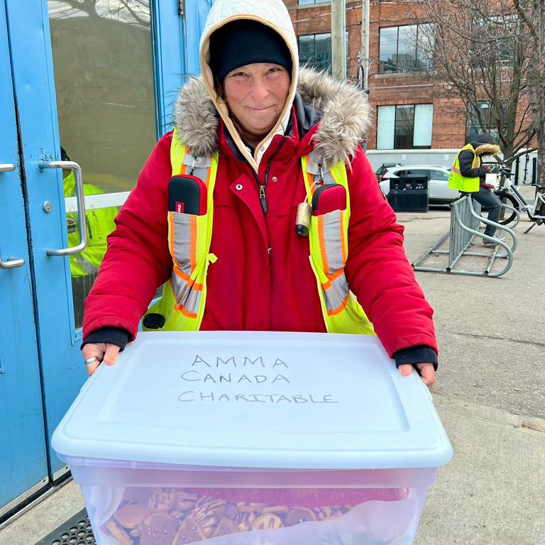 St. Felix staff member holding big box of cookies from Amma Canada